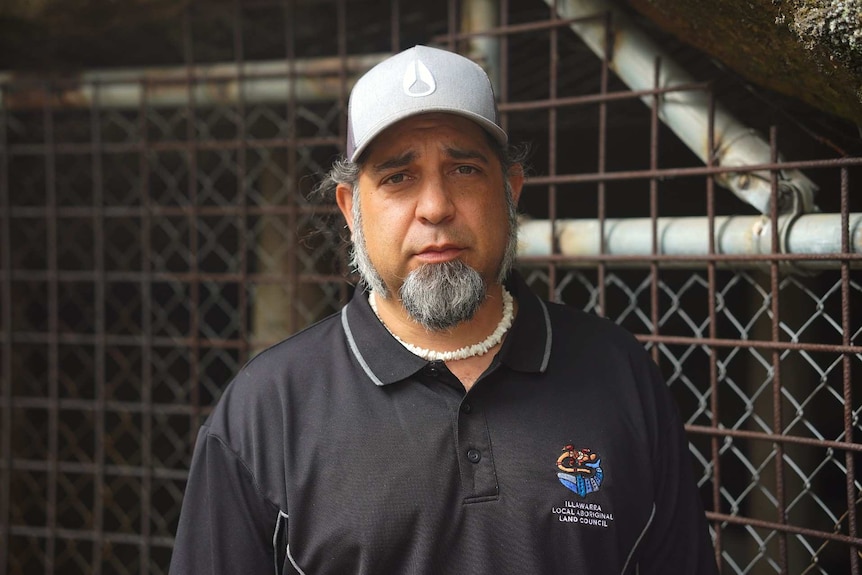 A man standing in front of a metal gate with a sad look on his face.