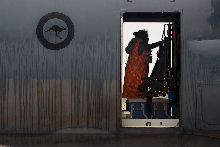 A woman is framed in the doorway of the plane as she climbs onboard