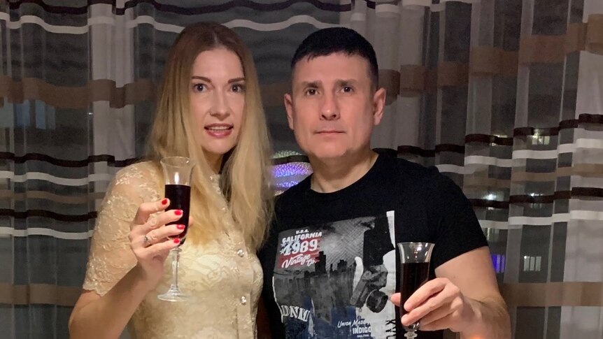 A woman with long, blonde hair and a man with dark hair wearing a black T-shirt. Both are toasting the new year.