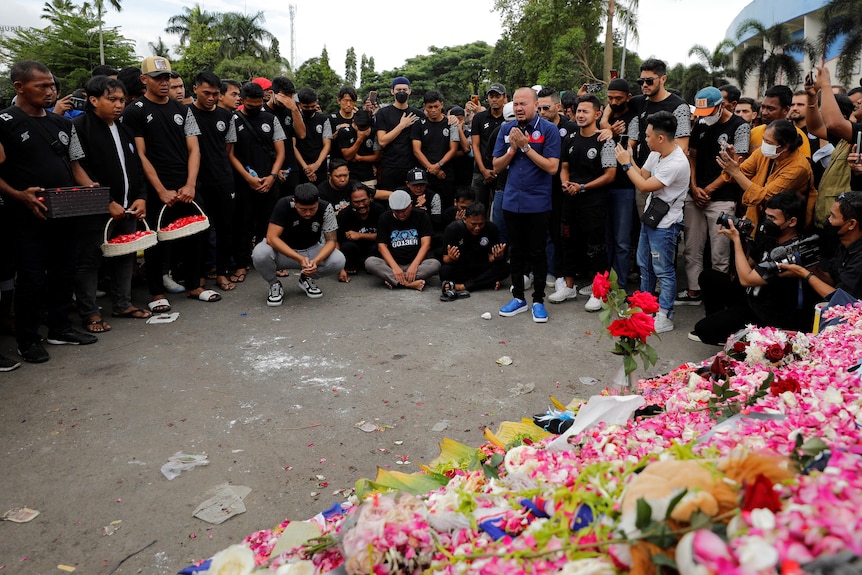 Les gens présentent leurs condoléances à un mémorial de fleurs aux victimes d'une bousculade