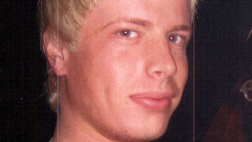 A blonde man looks at the camera.