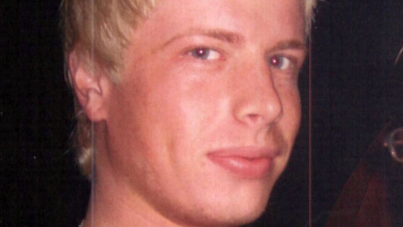 A blonde man looks at the camera