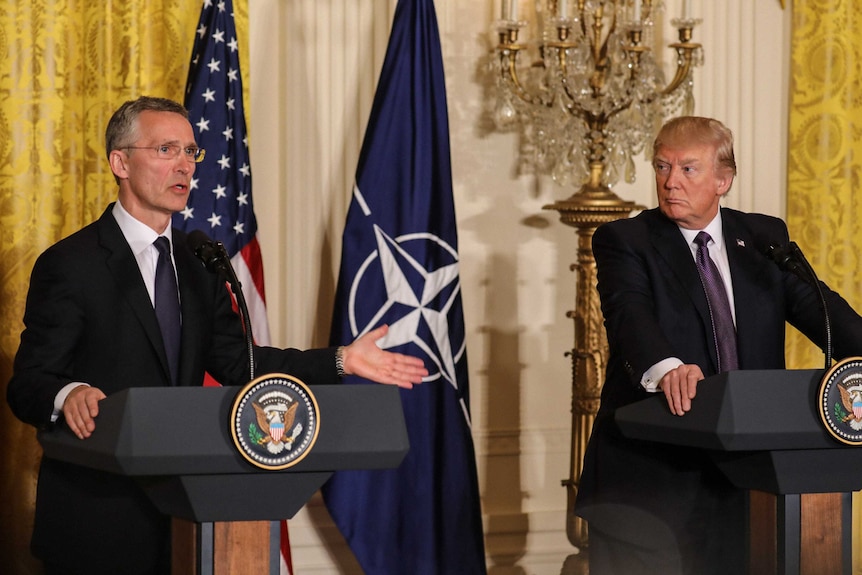 Donald Trump watches on as NATO Secretary General Jens Stoltenberg speaks to the media.