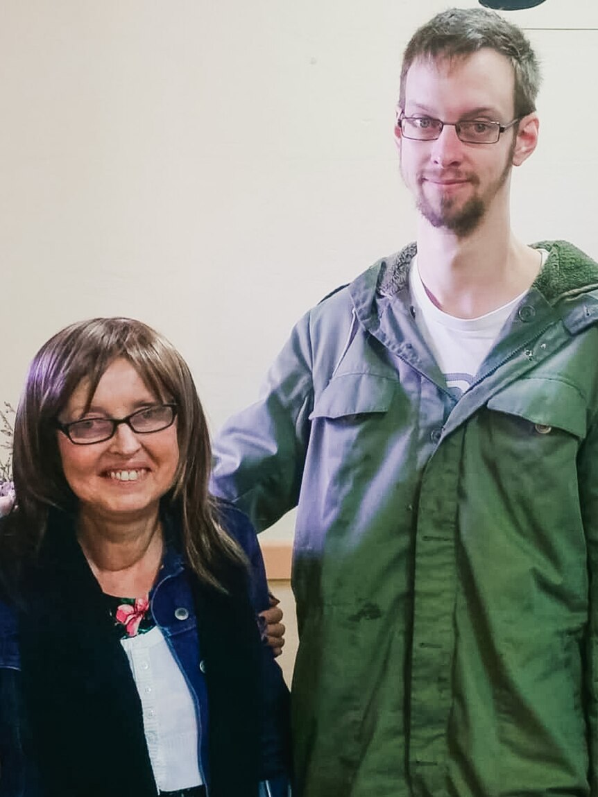 A tall man with a beard and glasses stands next to a shorter older women smiling.