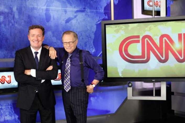 Piers Morgan and Larry King stand in front of a CNN logo.