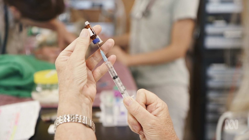 A syringe drawing medicine out of a vial