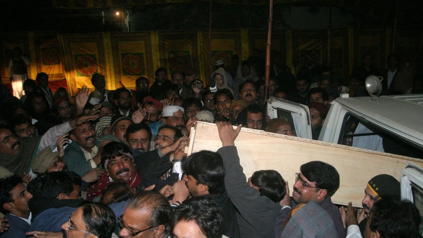 Supporters of Pakistan's assassinated opposition leader Benazir Bhutto unload her coffin.