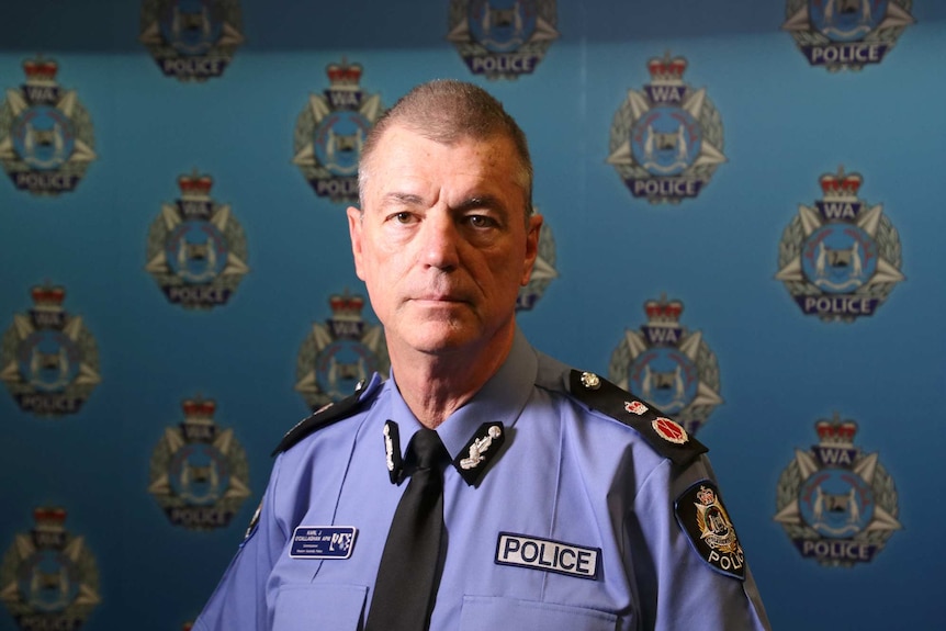 Police commissioner Karl O'Callaghan looks at the camera, with the WA Police logo in the background.