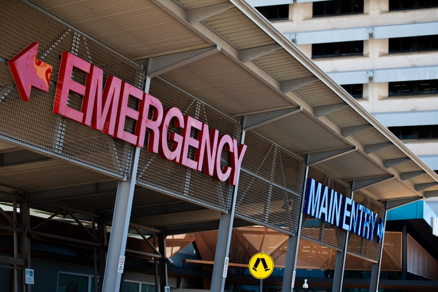The front of a hospital building featuring signs saying "emergency" and "main entry".