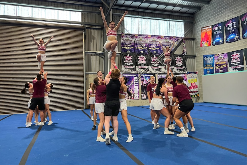 Cheerleaders hold each other up in the middle of a routine.