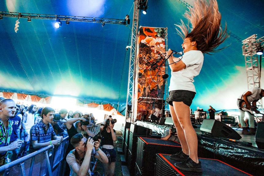 A female singer's hair is thrown up as she performs on a stage in a tent.