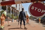 A Malian police officer stands guard as cleaners work outside the Radisson Blu hotel in Bamako