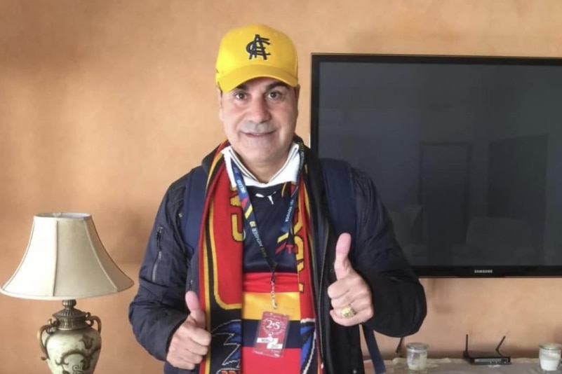 A man in an Adelaide Crows cap gives the thumbs up.