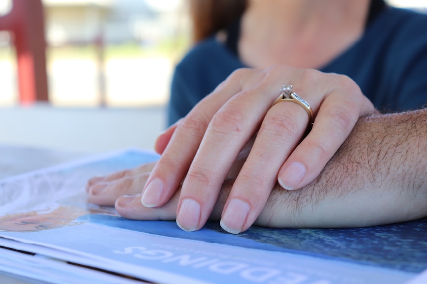 Close-up of Kerri Brown's hand with engagement ring on top fiance Brett Halford's hand.