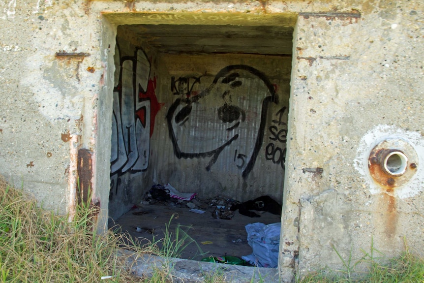 Graffiti and rubbish inside a small concrete structure