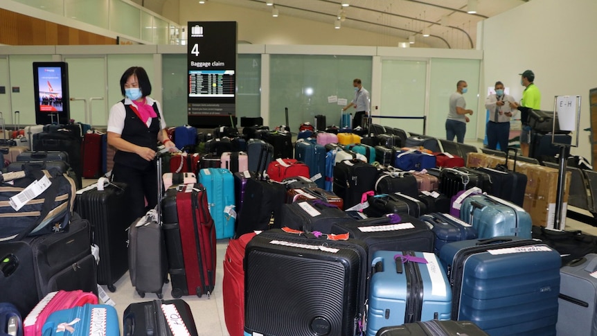 A woman stands next to a large number of travel bags