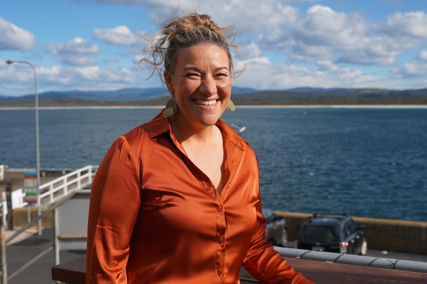 A woman in an orange silk blouse smiling