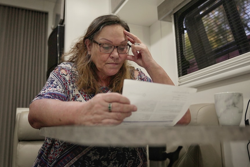 Kim Ellison looks down at a print out of an invoice.