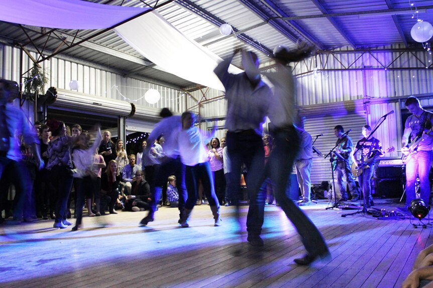 A live band play as people in jeans and long sleeve tops spin around the dance floor
