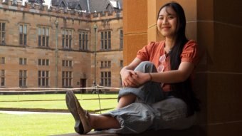 Tra Nguyen sitting on a wall at uni