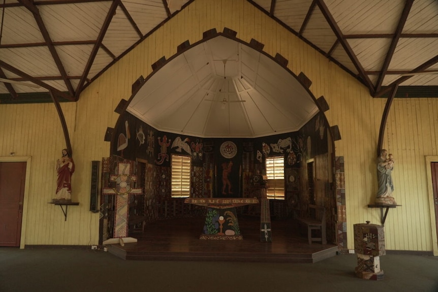 Colourful Aboriginal art is painted around a church altar and sanctuary