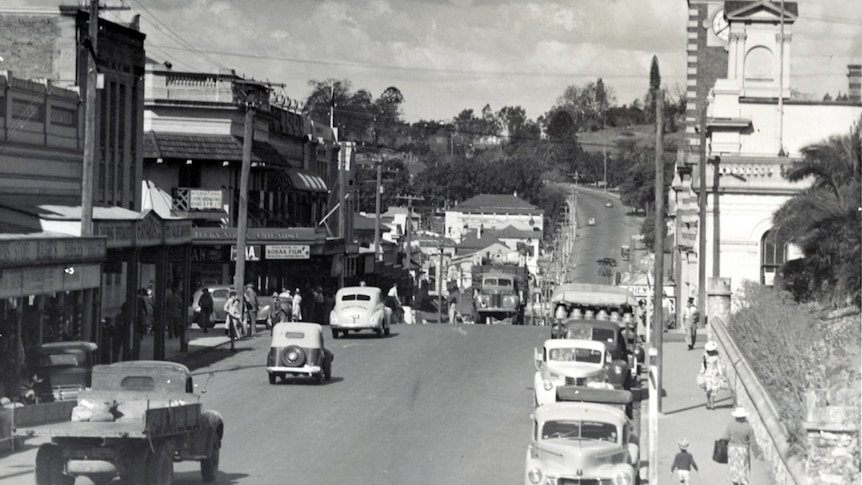 A black and white photo of a busy road full of 1940's cars.