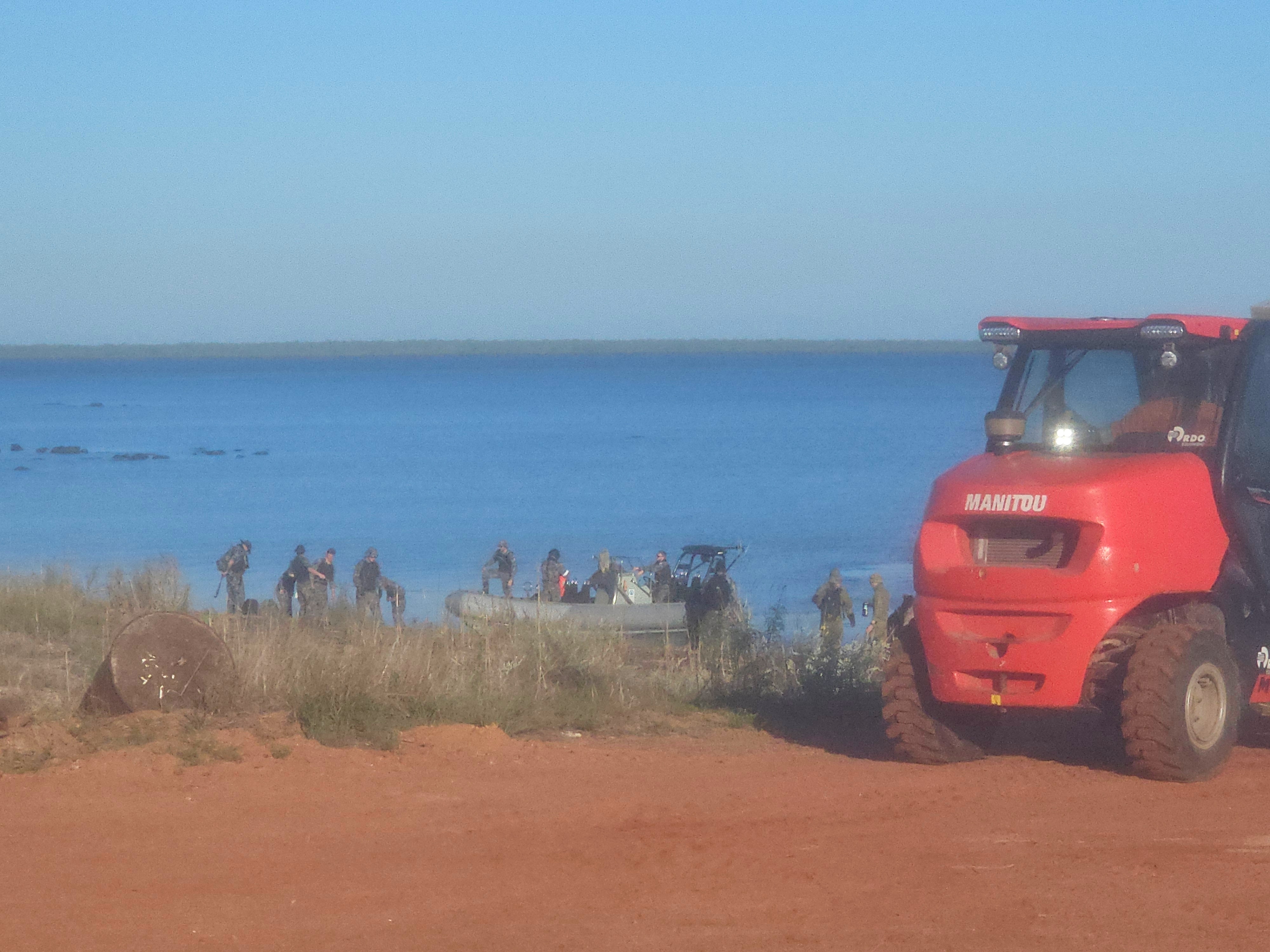Blurred shot of men on a beach near an inflatable boat.