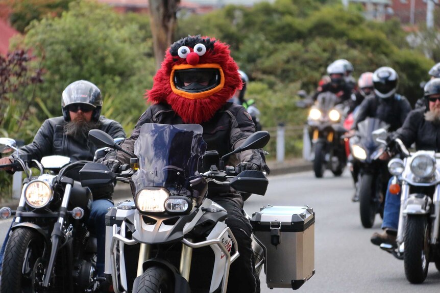 A motorcycle rider in a mask takes part in the Hobart toy run