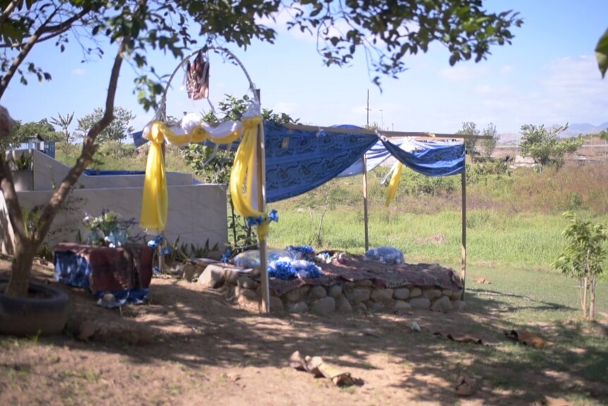 Brightly coloured cloth is strung over a grave.