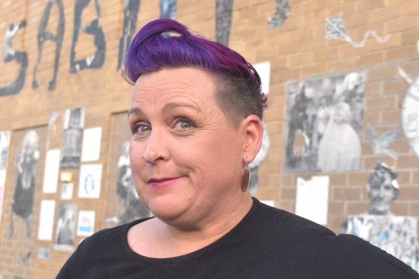 A smiling woman with short, purple hair