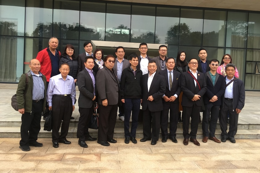 A group of people in front of large glass windows with Mr Wong at the front centre.