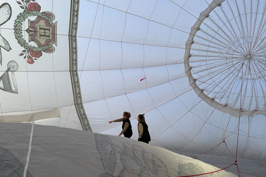 Two women walk around inside a hot air balloon envelope