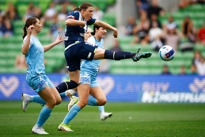 A soccer player wearing dark blue pokes out her toe reaching for the ball