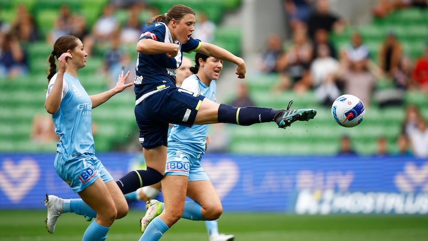 A soccer player wearing dark blue pokes out her toe reaching for the ball