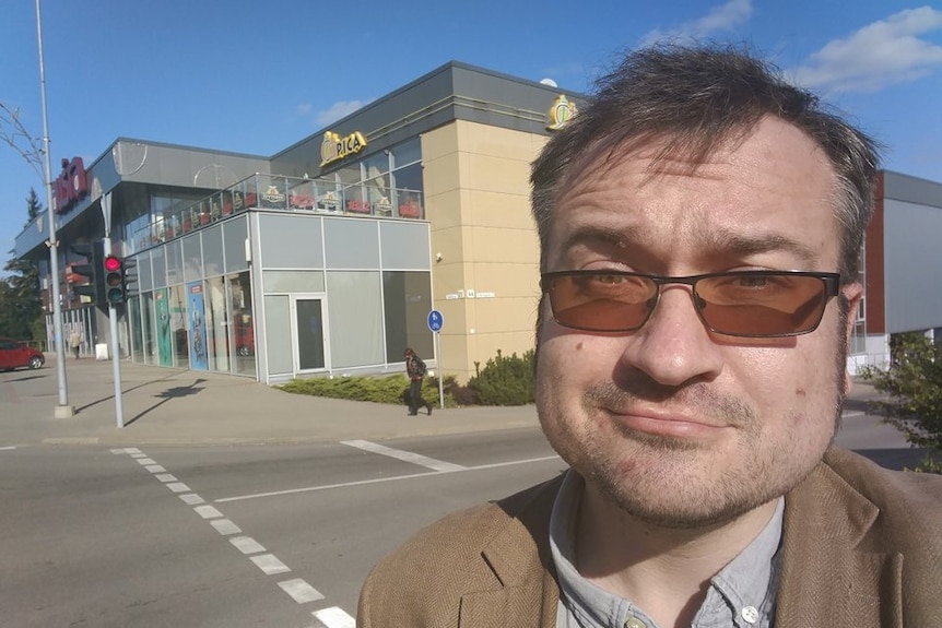 Selfie of journalist posing in front of shopping centre.