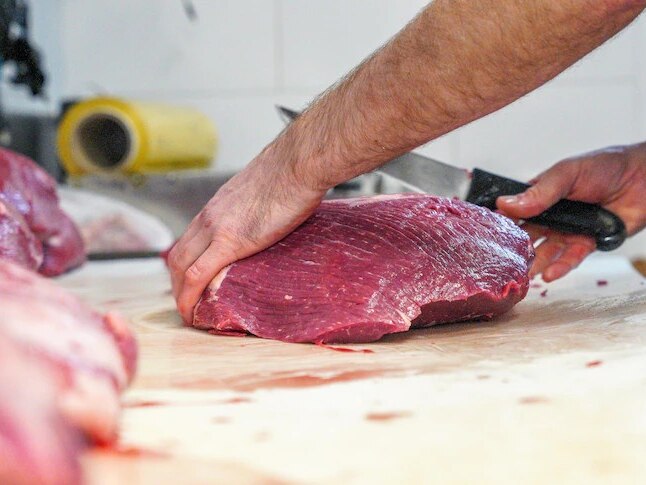 butcher cutting up piece of beef