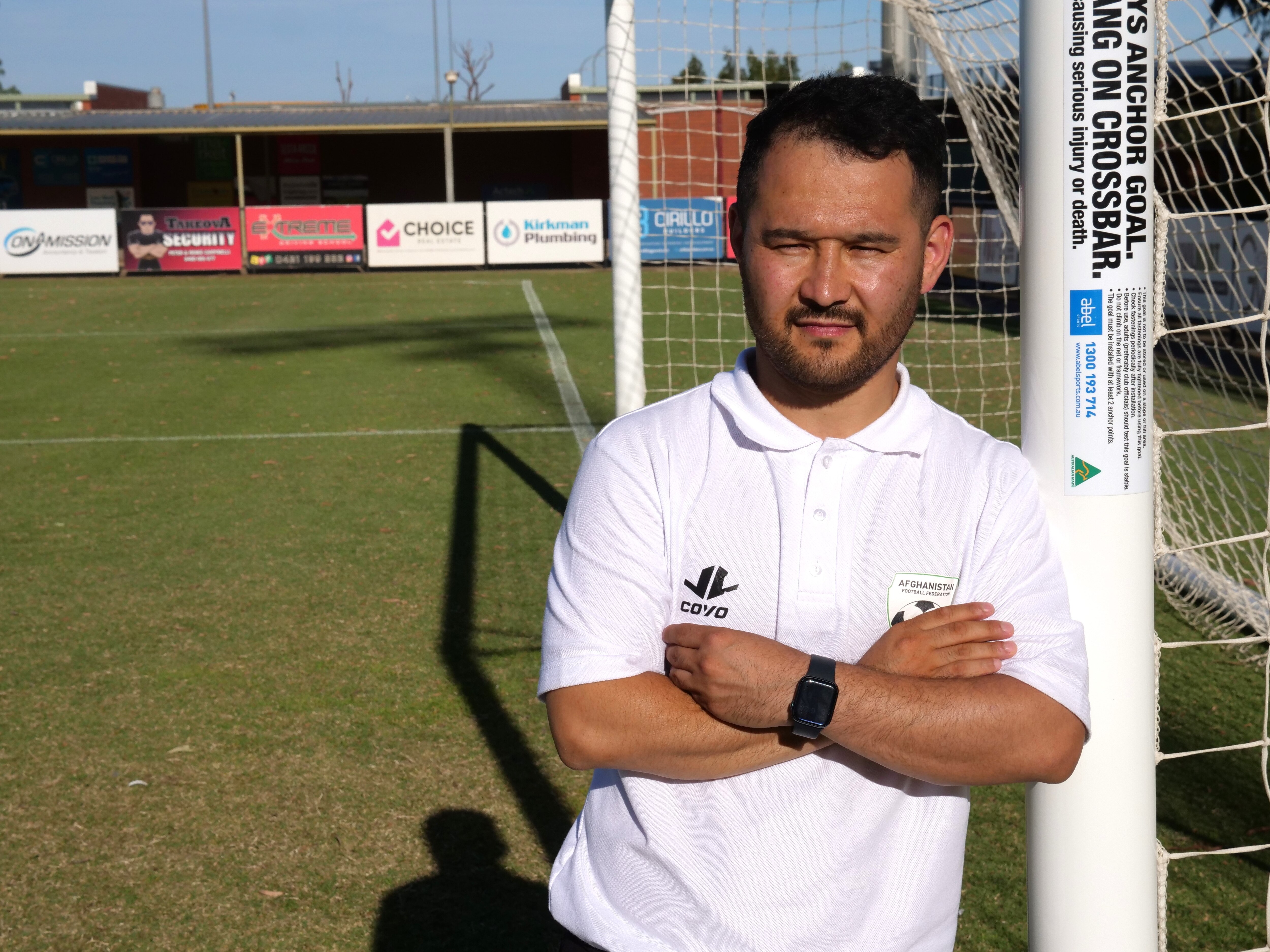 A man leaning on a football goal post