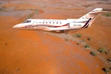 RFDS jet in the air, red dirt in the background.