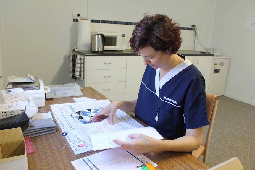 A woman sits at a table checking paperwork