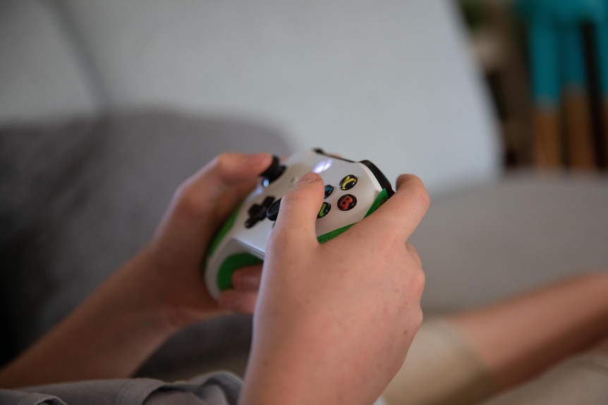 Close up of a teenage boys hands on an Xbox controller