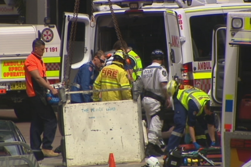 Rescue workers move when who were injured in a crane collapse into ambulances.