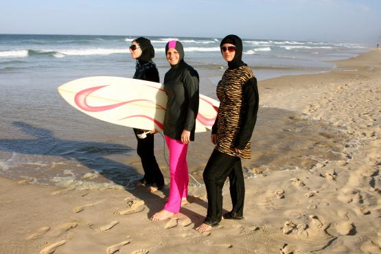 Islamic swimwear worn by three women holding a surfboard