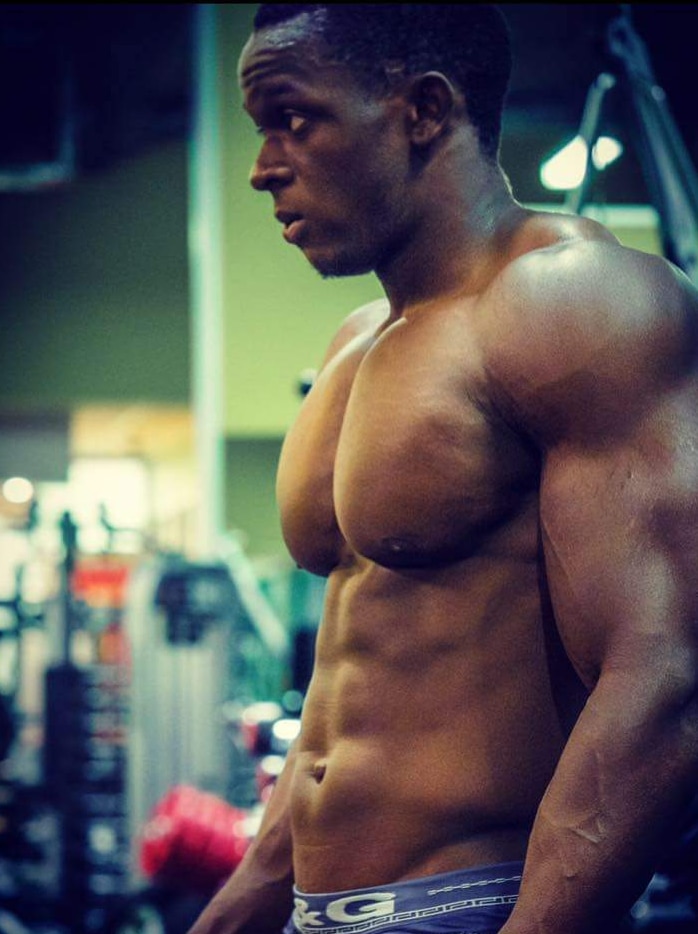 Bodybuilder Yusuf Kamara stands in the gym.