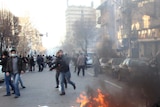 A rubbish bin burns as a protester runs past in Tehran