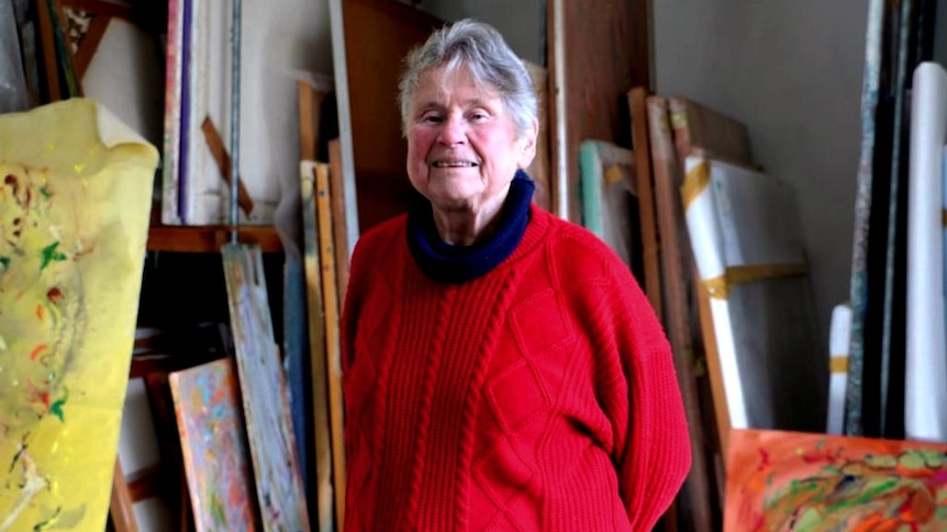 Barbara McKay stands in her studio in front of numerous works.