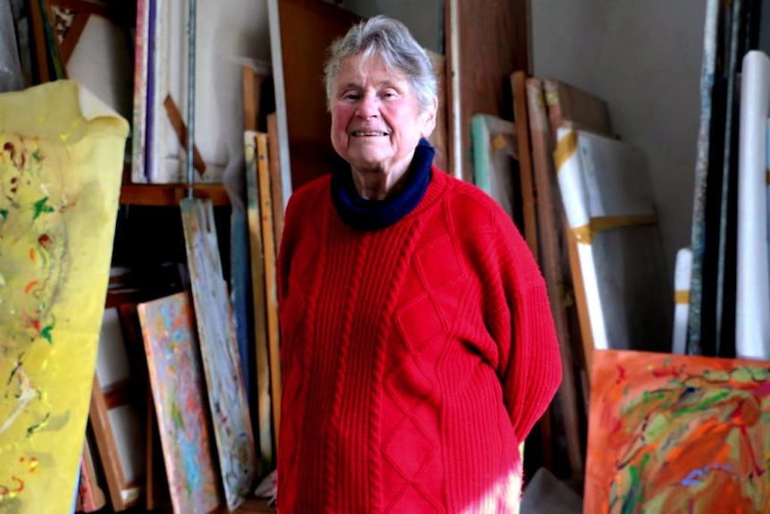 Barbara McKay stands in her studio in front of numerous works.