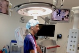 Staff member stands under the lighting in the operating theatre.