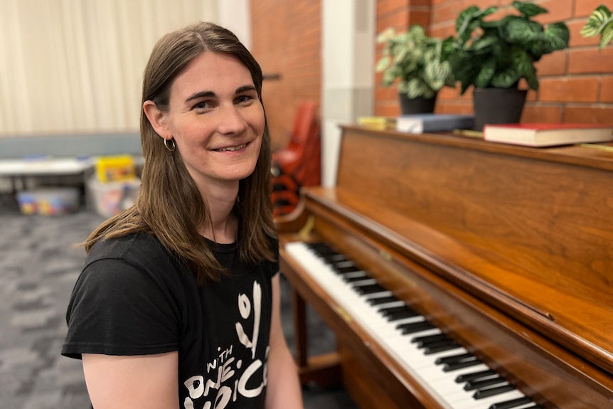 Woman with long brown hair smiles while sitting at a piano