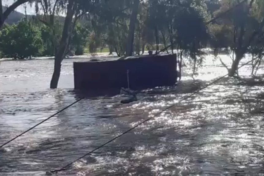 A shipping container floating down a flooded river