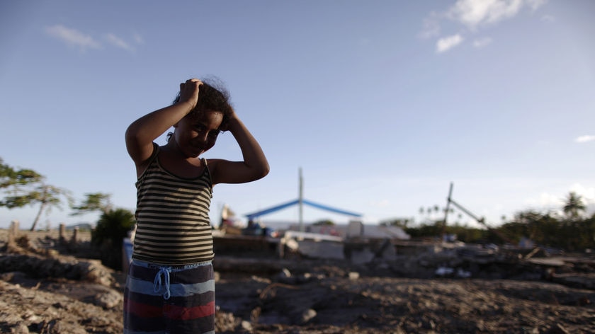 A girl stands in disbelief in front of the remains of her tsunami-destroyed home in Samoa